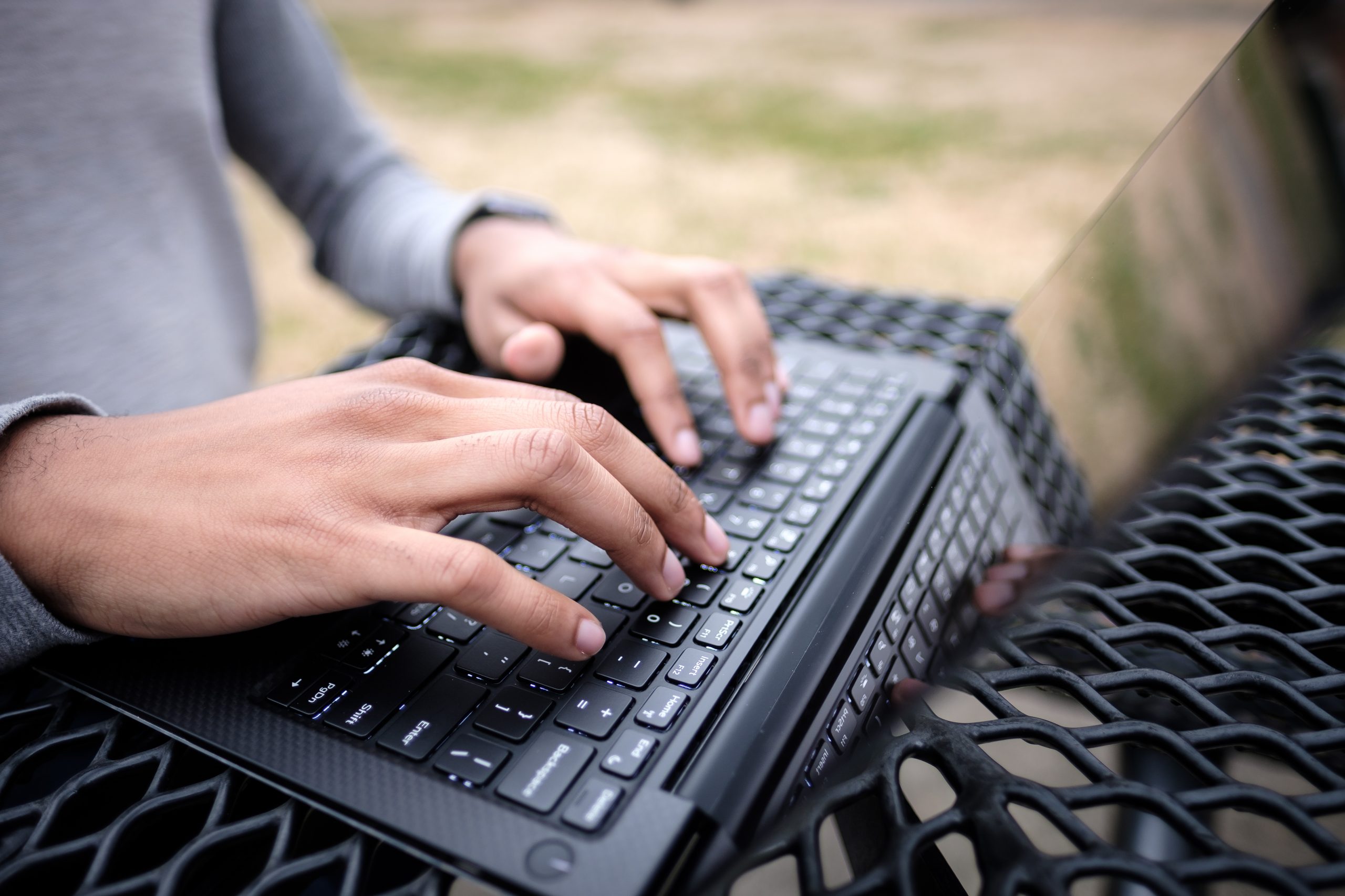 Person typing on laptop on outside table