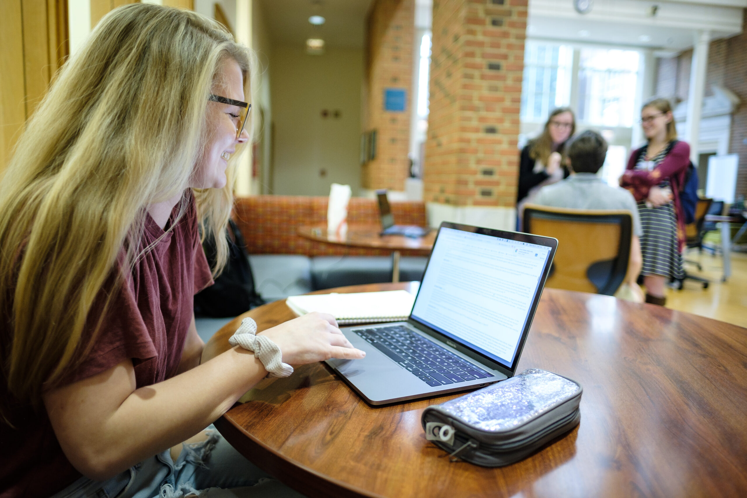 Student in the library browses her open laptop, sitting at a table.